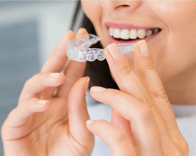 A woman holding clear aligners.