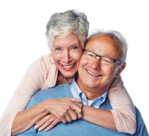 An elderly couple, embracing and smiling.