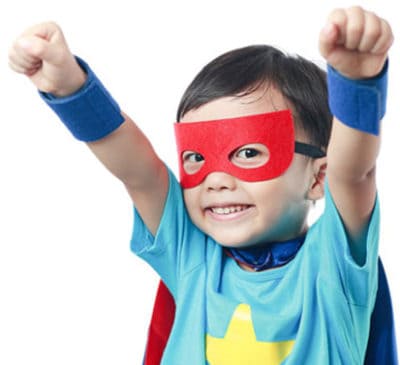 A young boy wearing a super hero cape and mask.